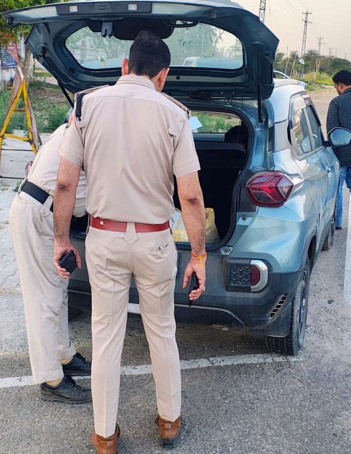 सड़क पर रोके गए वाहन की बारीकी से जांच करती पुलिस टीम