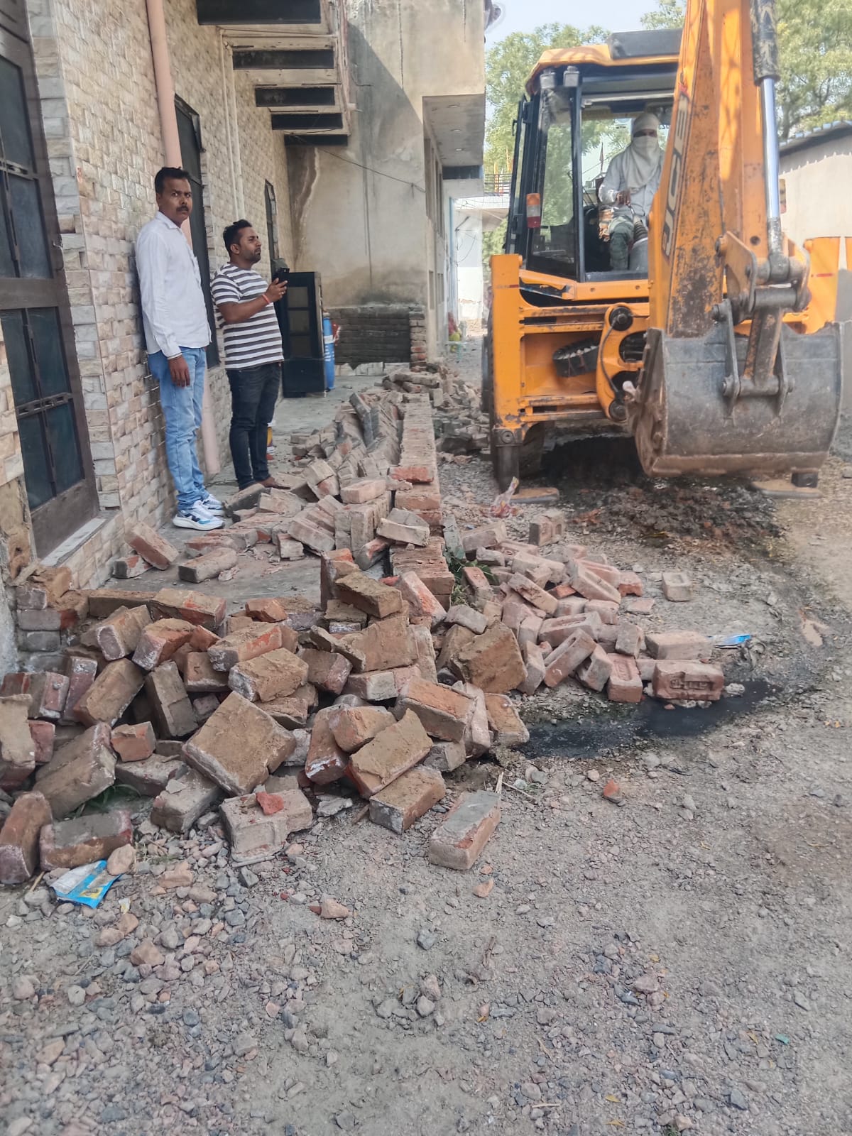 नारनौल के मोहल्ला गुदड़ी में अतिक्रमण हटाते हुए नगर परिषद की टीम, जेसीबी से अवैध दीवार को तोड़ा गया।