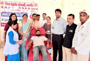 मानव सेवा की मिसाल: रक्तदान करते युवक के साथ उपस्थित अधिकारी व समाजसेवी