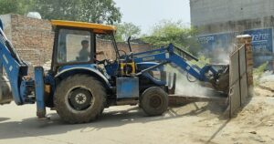 जेसीबी से अतिक्रमण हटाते कर्मचारी।