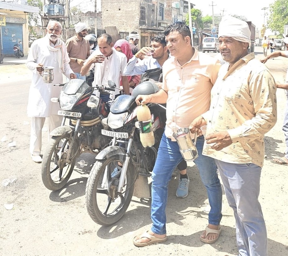 ताऊ देवीलाल चौक निजामपुर में राहगीरों को ठंडा पानी पिलाते समाजसेवी और युवा।