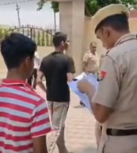 नारनौल में गर्ल स्कूल के सेंटर के बाहर खड़ी छात्रा के रोल नंबर देखते पुलिसकर्मी