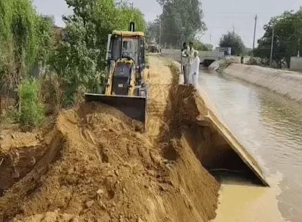 भोडियाखेड़ा में टूटी सिरसा ब्रांच नहर को ठीक करने में जुटा जेसीबी चालक।