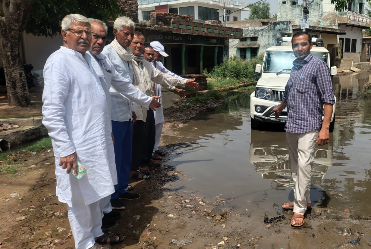 सड़क पर जमा गंदे पानी का निरीक्षण करते हुए नेताजी अतरलाल व ग्रामीण।